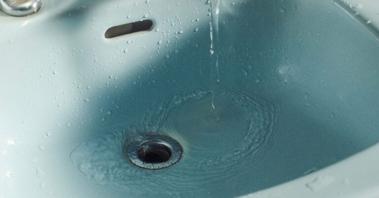Close-up of water flowing from a faucet into a bathroom sink.